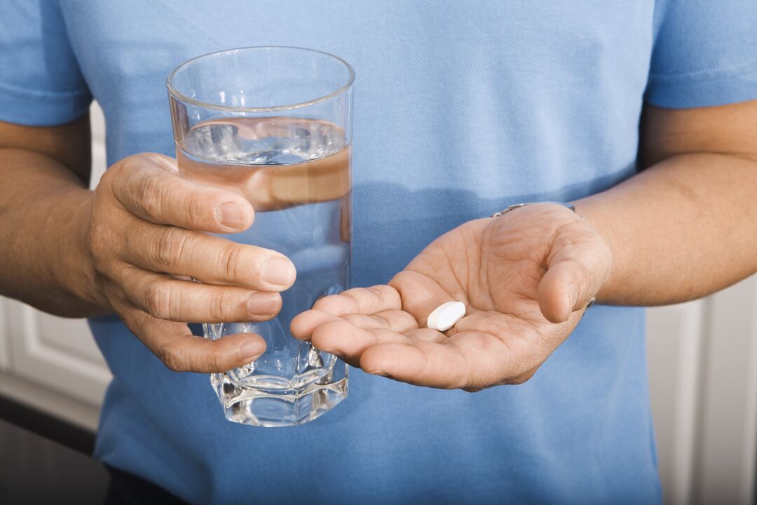 un hombre bebiendo una pastilla para los parásitos